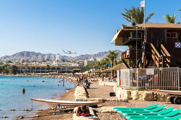 Eilat, İsrail 7 Kasım 2017: şehir beach, Eilat turistler ve kentsel beyaz binalar ve dağ zirveleri, Eilat, İsrail arka plan üzerinde açılış çift motorlu turboprop uçağı ile. Seyahat ve Turizm kavramı 