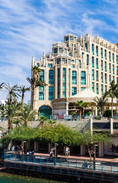Eilat, İsrail 7 Kasım 2017: Dolgu, insanlar, dükkanlar, palmiye ağaçları ve arka planda Eilat ünlü uluslararası tatil - İsrail southest şehir otel karmaşık Hilton ile Marina girişine