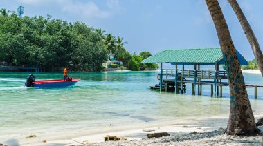 Maldivler 19 Kasım 2017: tropik ada bir ahşap demirleme, plaj, mavi bir lagün, Kaafu Atoll, Kuda Huraa Adası arka plan üzerinde beyaz kum ile. Seyahat ve Turizm kavramı