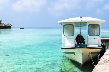 Hint Okyanusu ve mavi gökyüzü, küçük tropik ada, Maldivler temiz su karşı iskelede beyaz Motorlu tekne bağlı. Tatil hedef