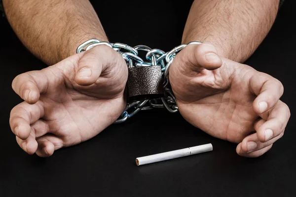Cigarrillos y mano de un hombre enredado en cadenas. El concepto de — Foto de Stock