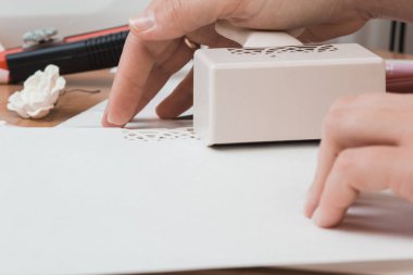 Scrapbooking için araçlar. Bir kadın kâğıdı kesmek için araçlarını kullanır.