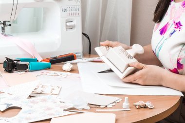 Scrapbooking için araçlar. Bir kadın kâğıdı kesmek için araçlarını kullanır.