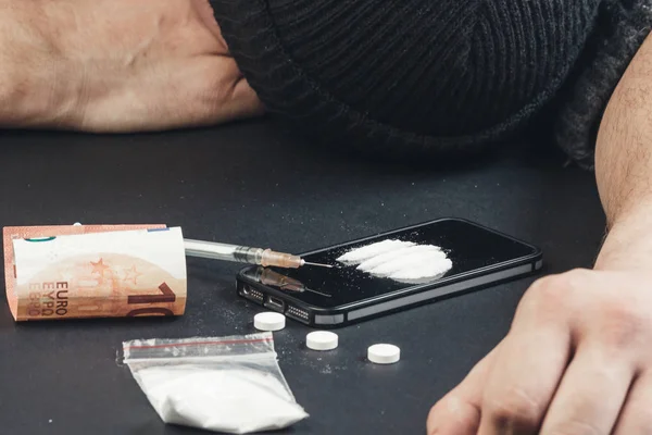 Homem viciado em drogas deitado na mesa de uma overdose de drogas. Conceito de dano de drogas. Criminalidade relacionada com a droga . — Fotografia de Stock