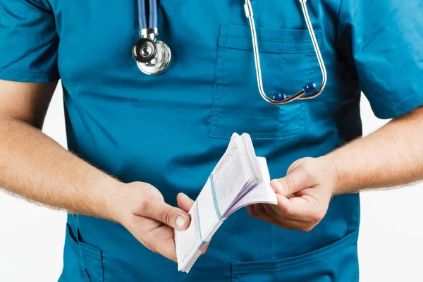 Médico com estetoscópio e notas e algemas de euro . — Fotografia de Stock