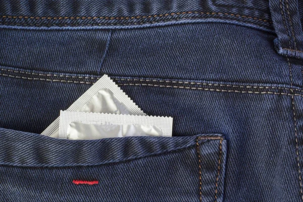 Презерватив в кармане синих джинсов. Презервативы — стоковое фото