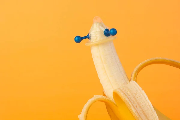 Kondom og banan på oransje bakgrunn. – stockfoto