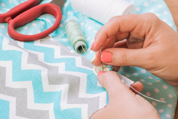 Фотография рук швеи при работе с тканевой тканью
