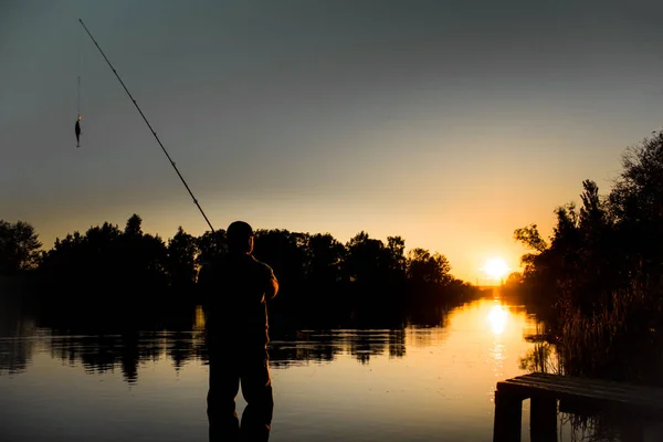 Pêche. tournant au coucher du soleil. Silhouette de pêcheur . — Photo