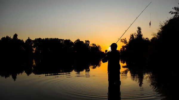 Fiske. spinning i solnedgången. Silhuetten av en fiskare. — Stockfoto