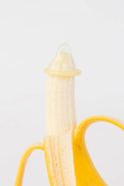 Beyaz arka planda kondom ve muz yakın planda.