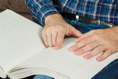 Kör adam Braille üzerinde yazılı bir kitap okuyordu. Dokunma, 