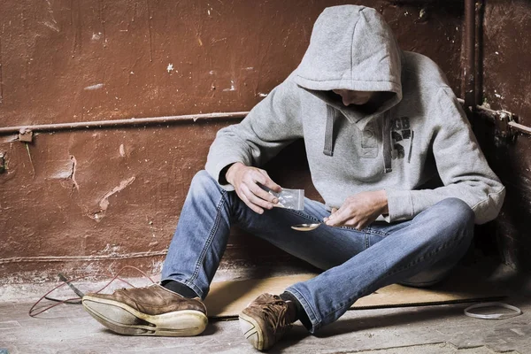 A young man makes heroin in, preparing to take heroin, pours her — Stock Photo, Image