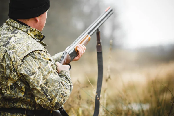 A man with a gun, against the background of an autumn forest. — Stock Photo, Image