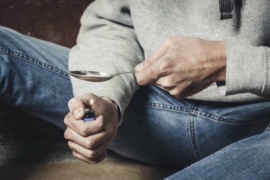 Bir uyuşturucu bağımlısı bir kaşık kokain erime elleri. Bir adam hol