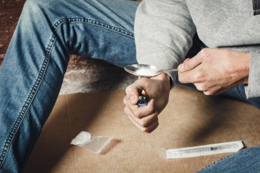 Bir uyuşturucu bağımlısı bir kaşık kokain erime elleri. Bir adam hol