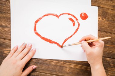 Kız bir kırmızı, küçük fırça, koyu arka plan kalbinde boyalar