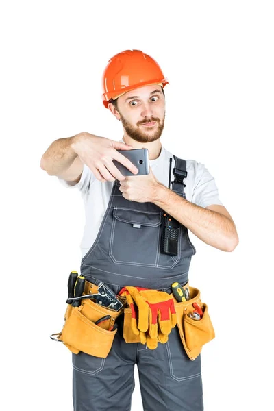 Smiling young construction worker showing a sign and taking a pi — Stock Photo, Image