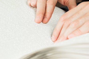 Kör adam Braille üzerinde yazılı bir kitap okuyordu. Braille kodu üzerinde parmak dokunmatik. Bir kitap Braille metinle.