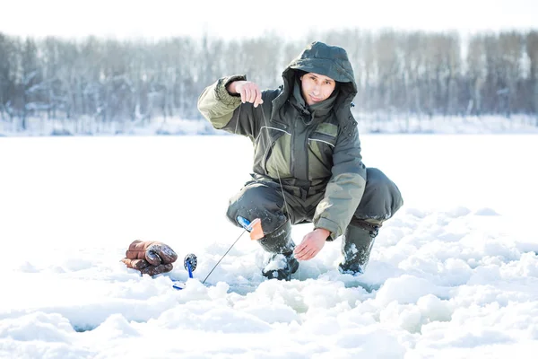 Egy fiatal férfi a egy lyuk a jég halászati. Téli halászat — Stock Fotó