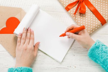 Sevgililer Günü teması. Eller en iyi görünümü. Paketlenmiş hediyeler, zarf, kalpleri hırpalanmış bir ahşap tablo.