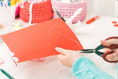 Sevgililer Günü teması. Eller kalp kağıt kesti. Hediyeler, hırpalanmış bir ahşap masa üstünde alet Paketli. İş yeri el yapımı süsler hazırlanması için