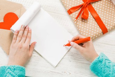 Sevgililer Günü teması. Eller en iyi görünümü. Paketlenmiş hediyeler, zarf, kalpleri hırpalanmış bir ahşap tablo.