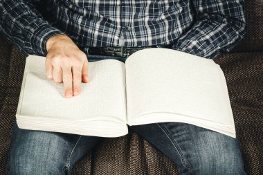 Kör adam Braille üzerinde yazılı bir kitap okuyordu. Braille kodu üzerinde parmak dokunmatik. Bir kitap Braille metinle.