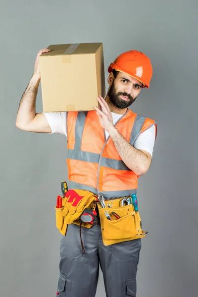 Man Builder Orange Helmet Cardboard Box His Hands Gray Background — Stock Photo, Image