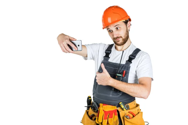 微笑的年轻建筑工人显示一个标志 并从电话中拍照 维修和施工 在白色背景上隔离 — 图库照片