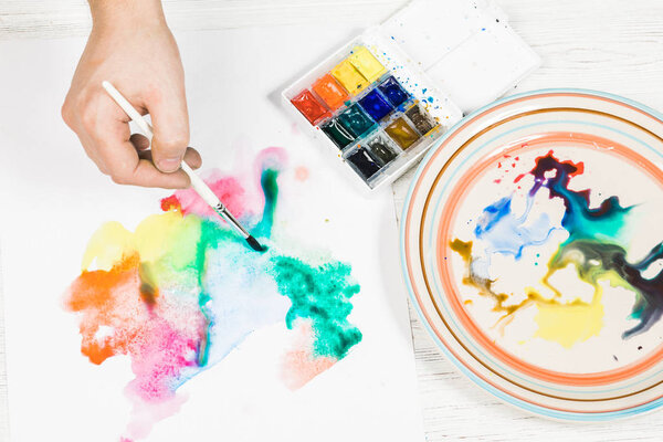 A person begins to paint on a sheet of paper with watercolors.