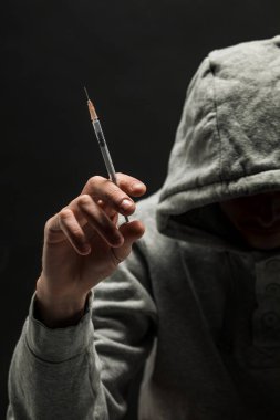 Kafasına gri kapüşonlu Addict koyu siyah bir arka plan üzerinde bağımlılığı muzdarip.