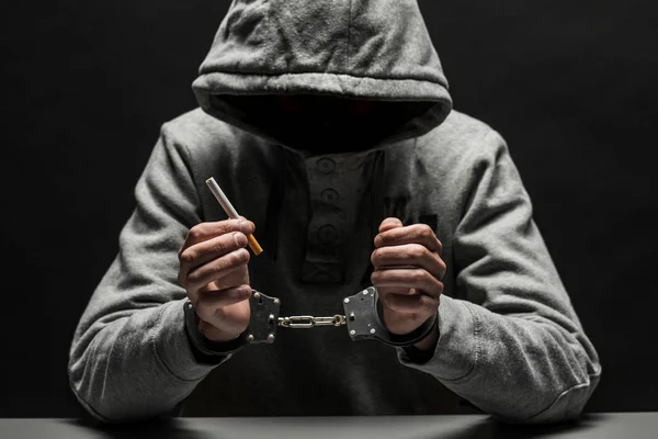 A drug addict arrested in handcuffs with a Smoking cigarette. Th — Stock Photo, Image