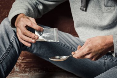 Genç bir adam eroin eroin almak hazırlanmasında, yapar, içine bir kaşık eroin dökülen. Suç ve uyuşturucu bağımlılığı kavramı.