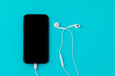 Mavi arka planda kulaklığı olan akıllı bir telefon. T 'den Görünüm