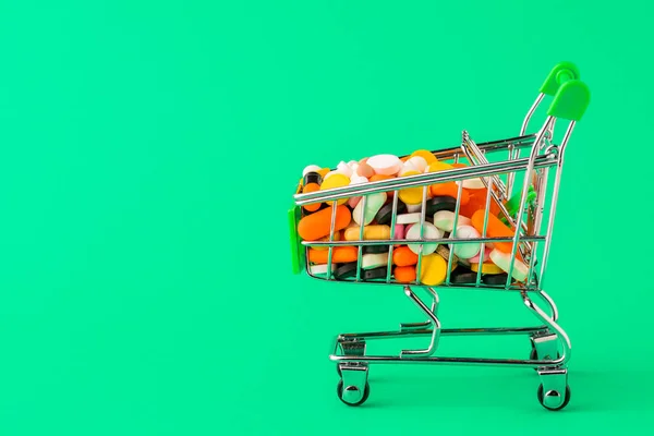 Comprimidos e cesta em um conceito de fundo verde de compra de drogas , — Fotografia de Stock