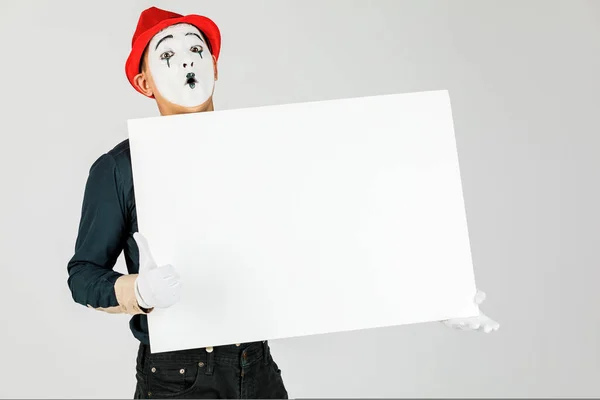 흰색 백그에 빈 흰색 보드를 들고 행복 한 마임 아티스트 — 스톡 사진