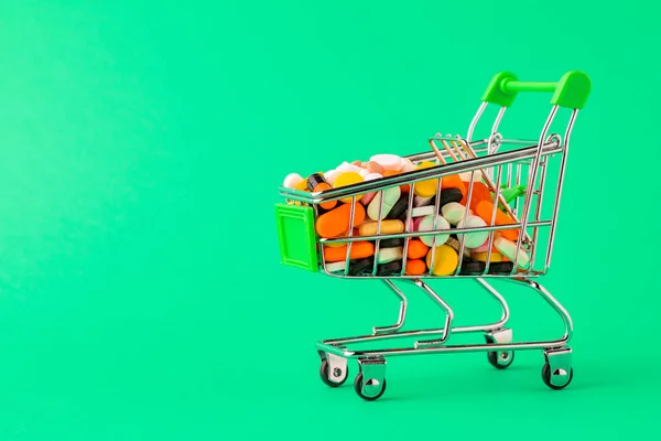 Comprimidos e cesta em um conceito de fundo verde de compra de drogas , — Fotografia de Stock