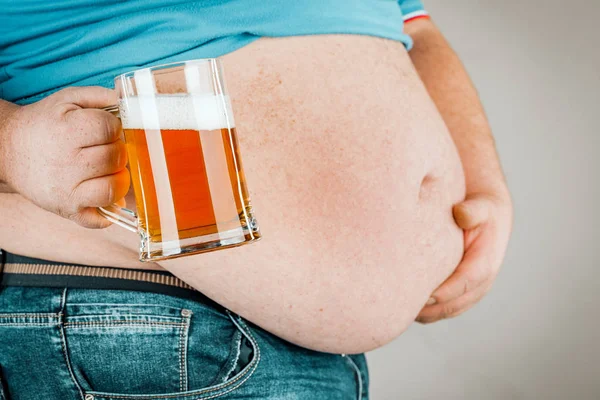 A man with a fat belly holding a glass of beer. On gray backgrou