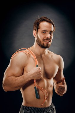 Yakışıklı bir erkek vücut geliştirici. Elinde bir ip var. Koyu renk bir B 'de.