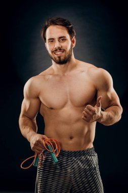 Yakışıklı bir erkek vücut geliştirici. Elinde bir ip var. Koyu renk bir B 'de.