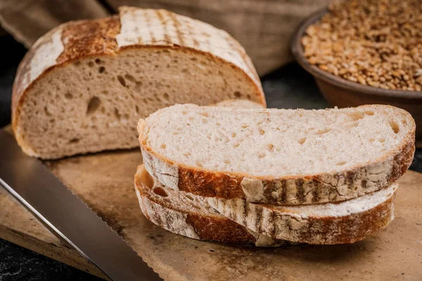 Nybakat bröd styckat i bitar på en träskiva — Stockfoto