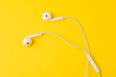 Sarı arka planda beyaz kulaklıklar. Müzik konsepti