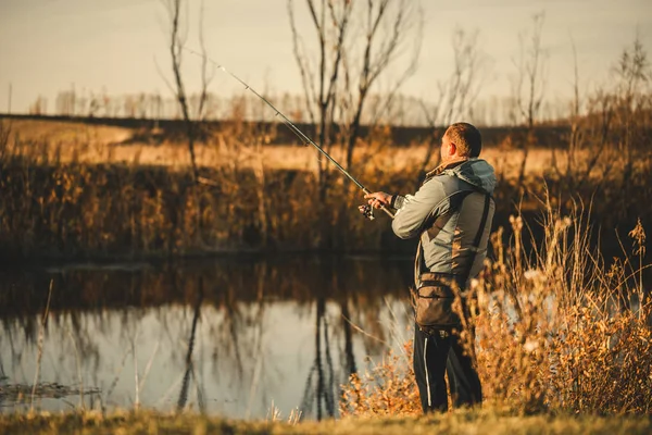 Un pêcheur homme pêche dans la rivière avec une canne à pêche . — Photo