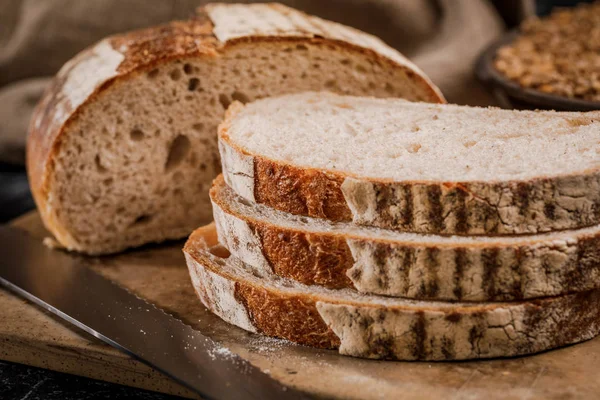 Świeżo upieczony chleb pokrojony na kawałki na drewnianej desce — Zdjęcie stockowe