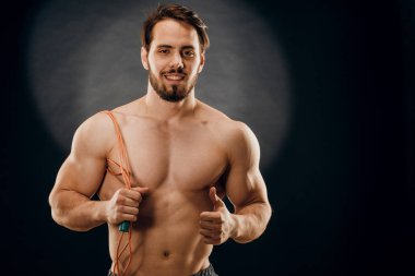 Yakışıklı bir erkek vücut geliştirici. Elinde bir ip var. Koyu renk bir B 'de.