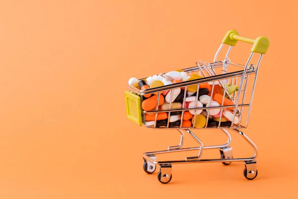 Comprimidos e carrinho de compras em um fundo amarelo Conceito de compra — Fotografia de Stock