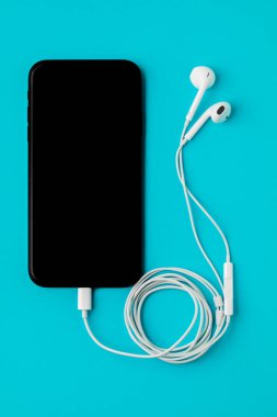 Mavi arka planda kulaklığı olan akıllı bir telefon. T 'den Görünüm