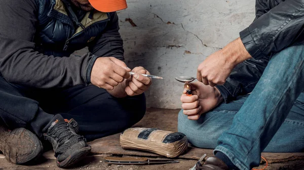 Два жалких человека готовят инъекции наркотиков в трущобах — стоковое фото