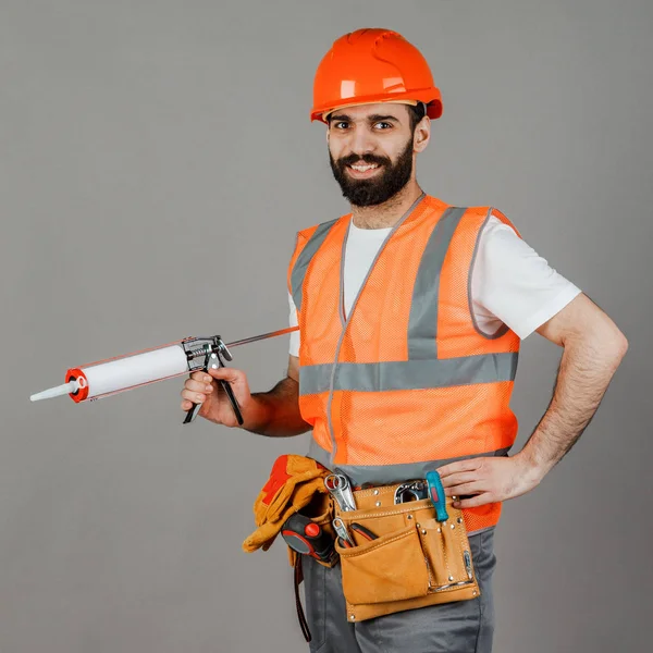 Middle-aged male builder in uniform on grey background — Stock Photo, Image